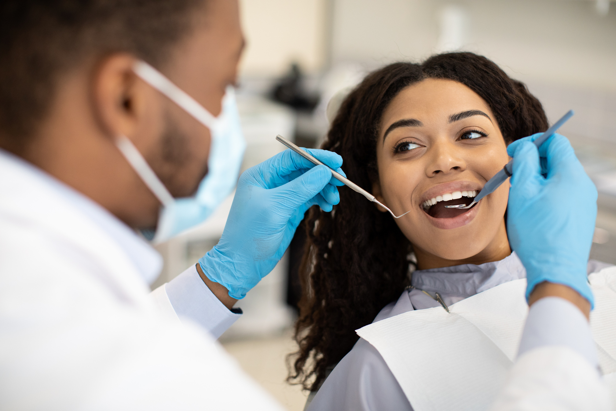 Young African American Woman Having Check up with Dentist in Modern Clinic